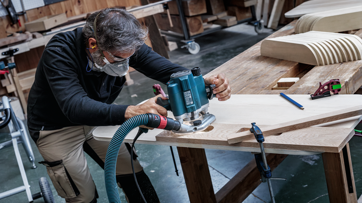 Object #200587673: 7437775_app_web_05 Person wearing safety equipment shapes wood using a power router in a workshop.