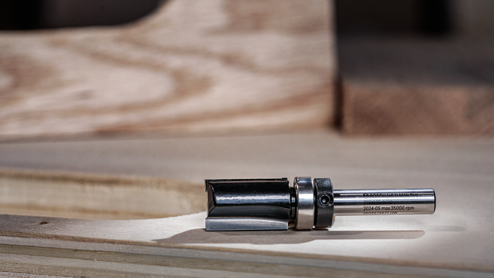 Object #200587674: 7437775_app_web_06 Metal router bit resting on a wooden work surface.