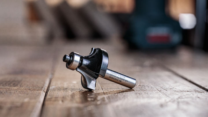 Object #200587702: 7437778_app_web_08 Router bit resting on a wooden surface in a workshop setting.