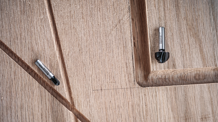 Object #200587711: 7437791_app_web_02 Two router bits rest on a carved wooden surface with grooved details.
