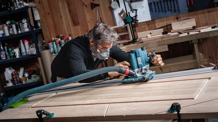 Object #200587714: 7437791_app_web_05 Person wearing safety equipment uses a power tool to rout grooves in a wooden door.