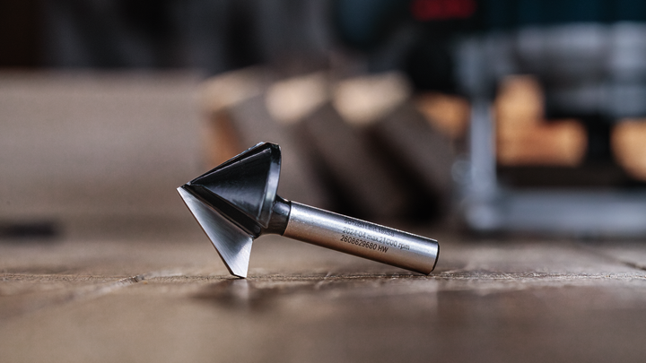 Object #200587728: 7437793_app_web_02 Chamfer router bit resting on a wooden surface in a workshop.