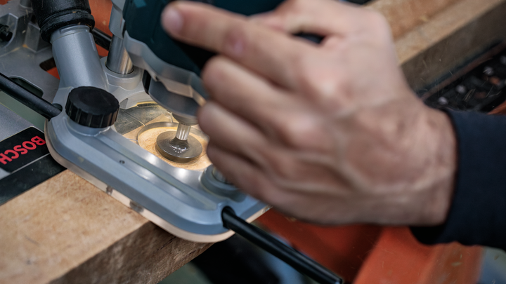 Object #200587730: 7437793_app_web_04 Person using a router to shape the edge of a wooden board.