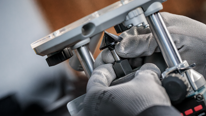 Object #200587731: 7437793_app_web_05 Person wearing safety equipment adjusts a router bit on a power tool.