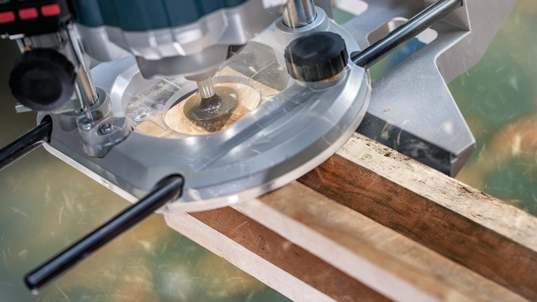 Wood router trimming the edge of a wooden board.