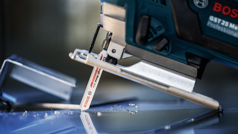 EXPERT Tough Metal thin T118AHM Jigsaw Blade, 3 pcs A jigsaw cuts through a sheet of glass with scattered glass shards nearby.