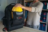 Bosch L-BOXX Contractor Backpack holding a yellow hard hat.