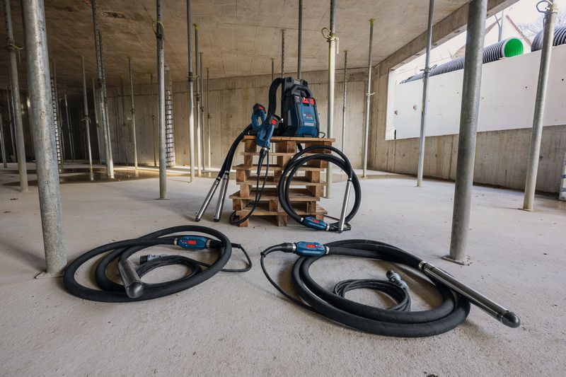 Construction site with two concrete vibrators and a backpack power supply on a pallet.