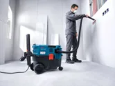 A person wearing safety equipment uses an all-purpose extractor to clean wall outlets.