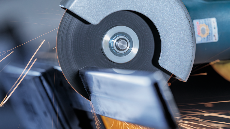 Cutting wheel slices through metal, sparks flying from the contact point.