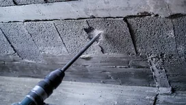 Rotary hammer drilling into a concrete wall, creating dust at the contact point.