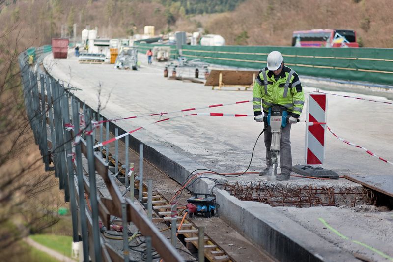 GSH 27 VC A person wearing safety equipment operates a breaker to demolish concrete on a bridge.